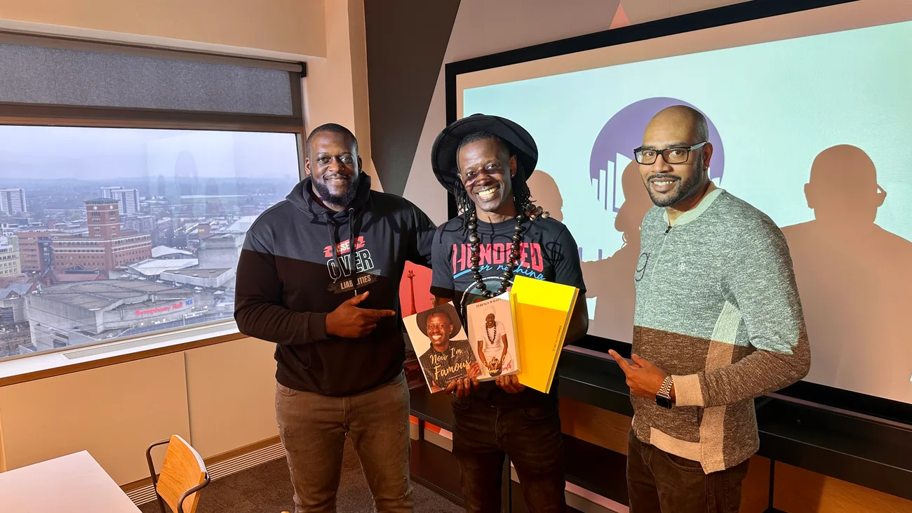 Darryl James with two people holding books at an event